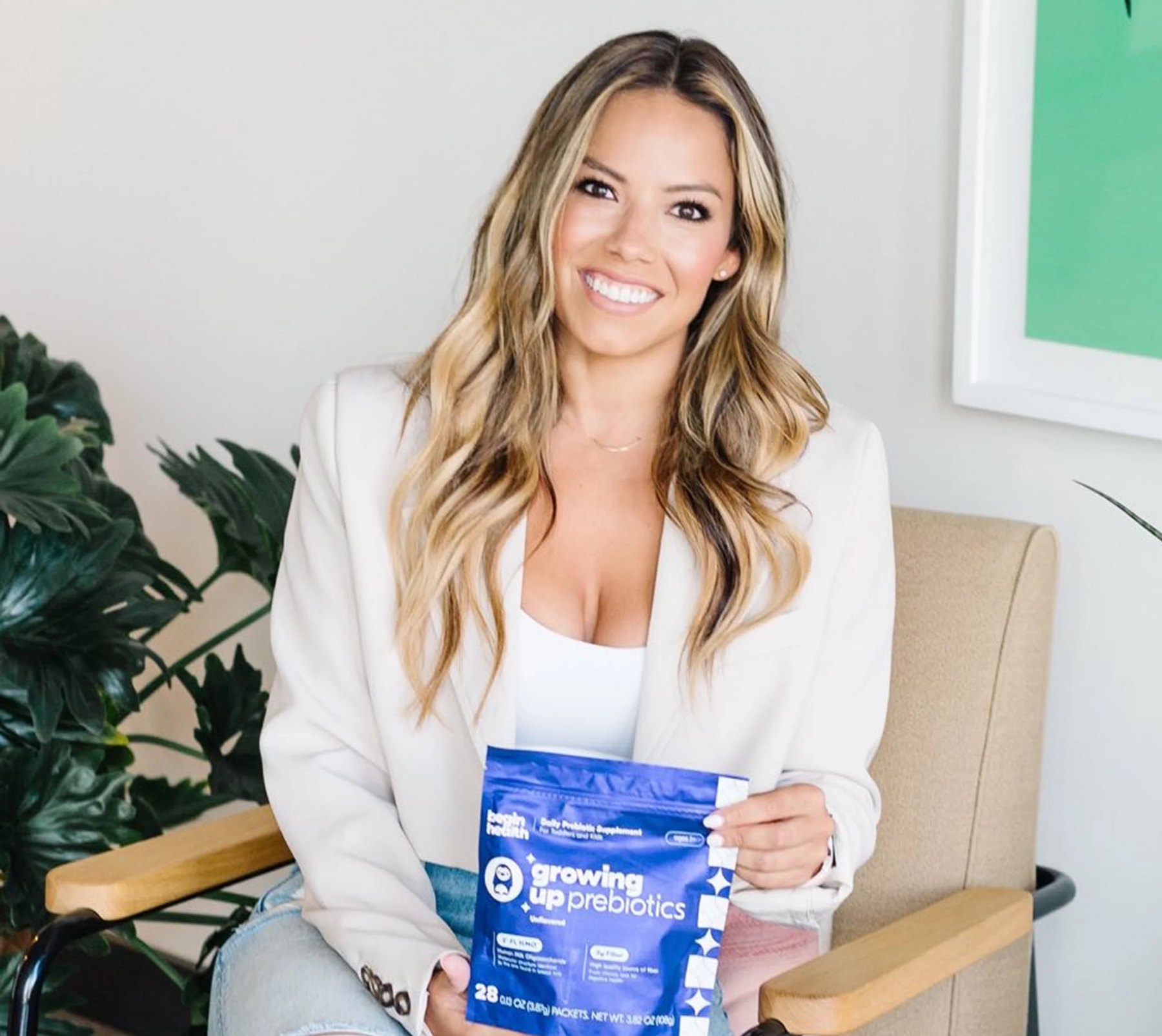 A smiling woman holds up a blue Begin Health pouch.