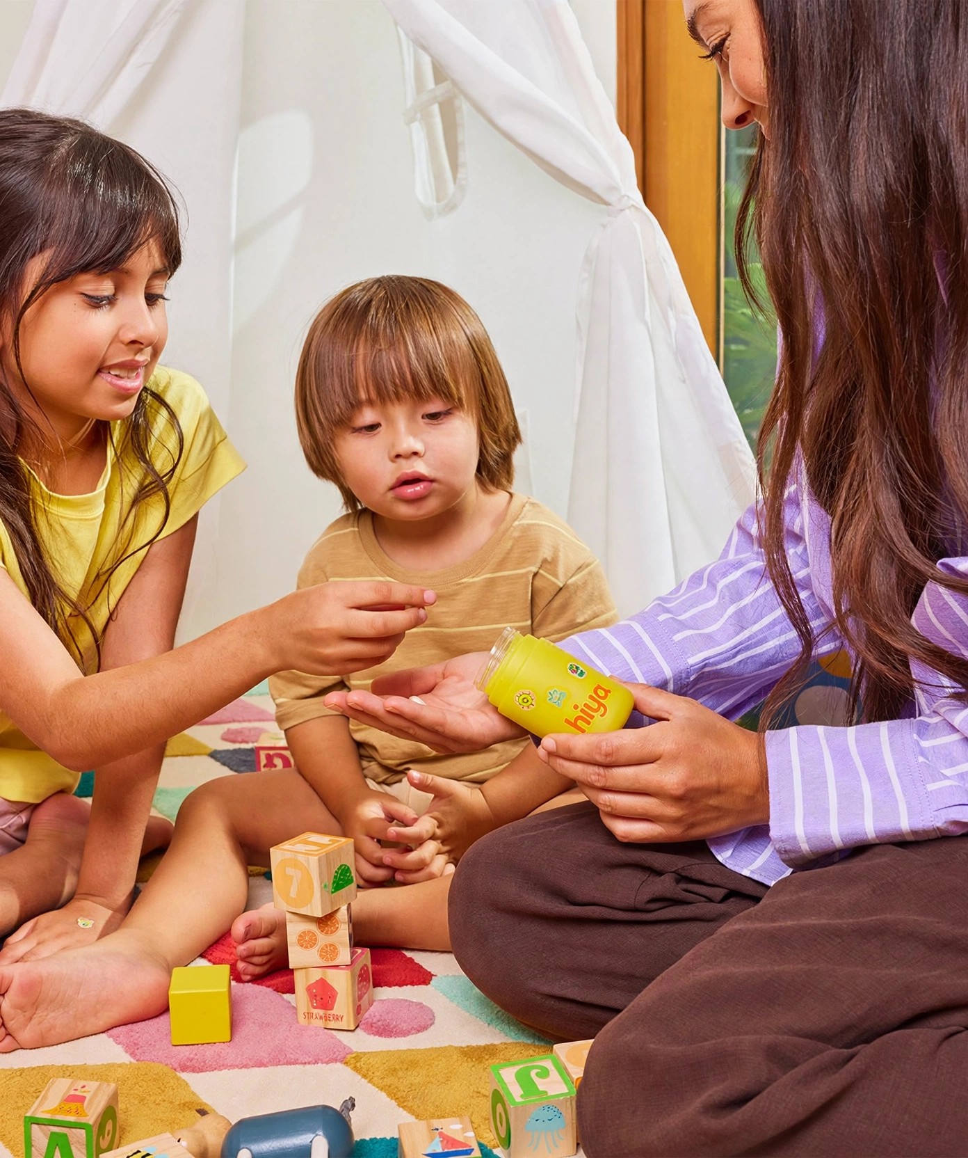 A mother shares Hiya chewables with children among toys.
