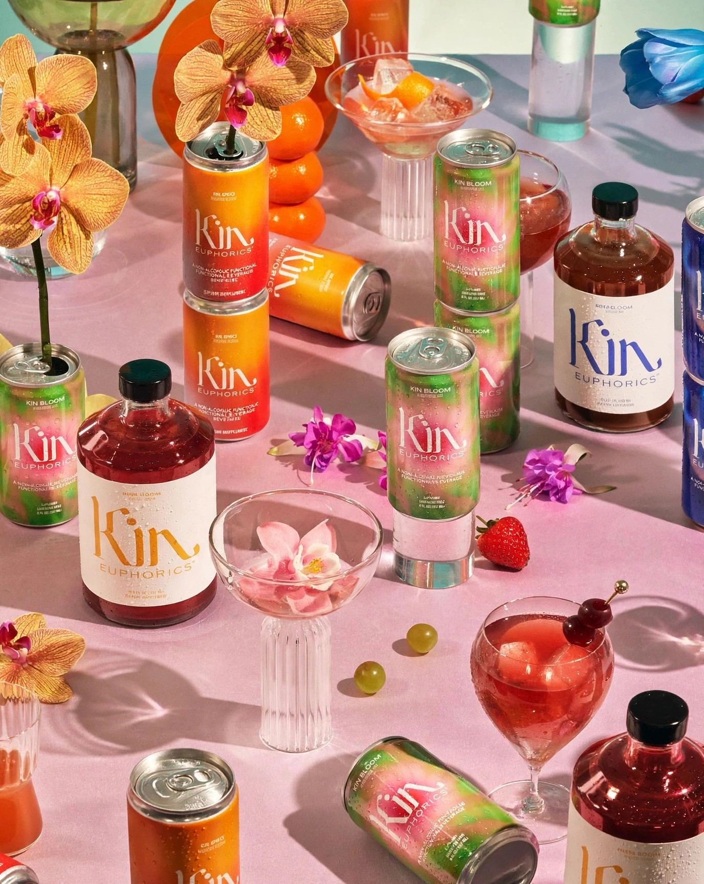 Assorted Kin beverages on pink table with orchids and fruit.