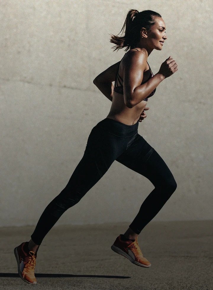 Fit woman mid stride during an outdoor run in daylight.