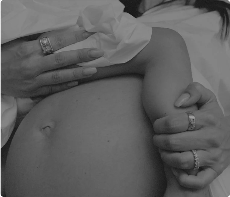 Maternal detail showing belly held by jeweled hands.