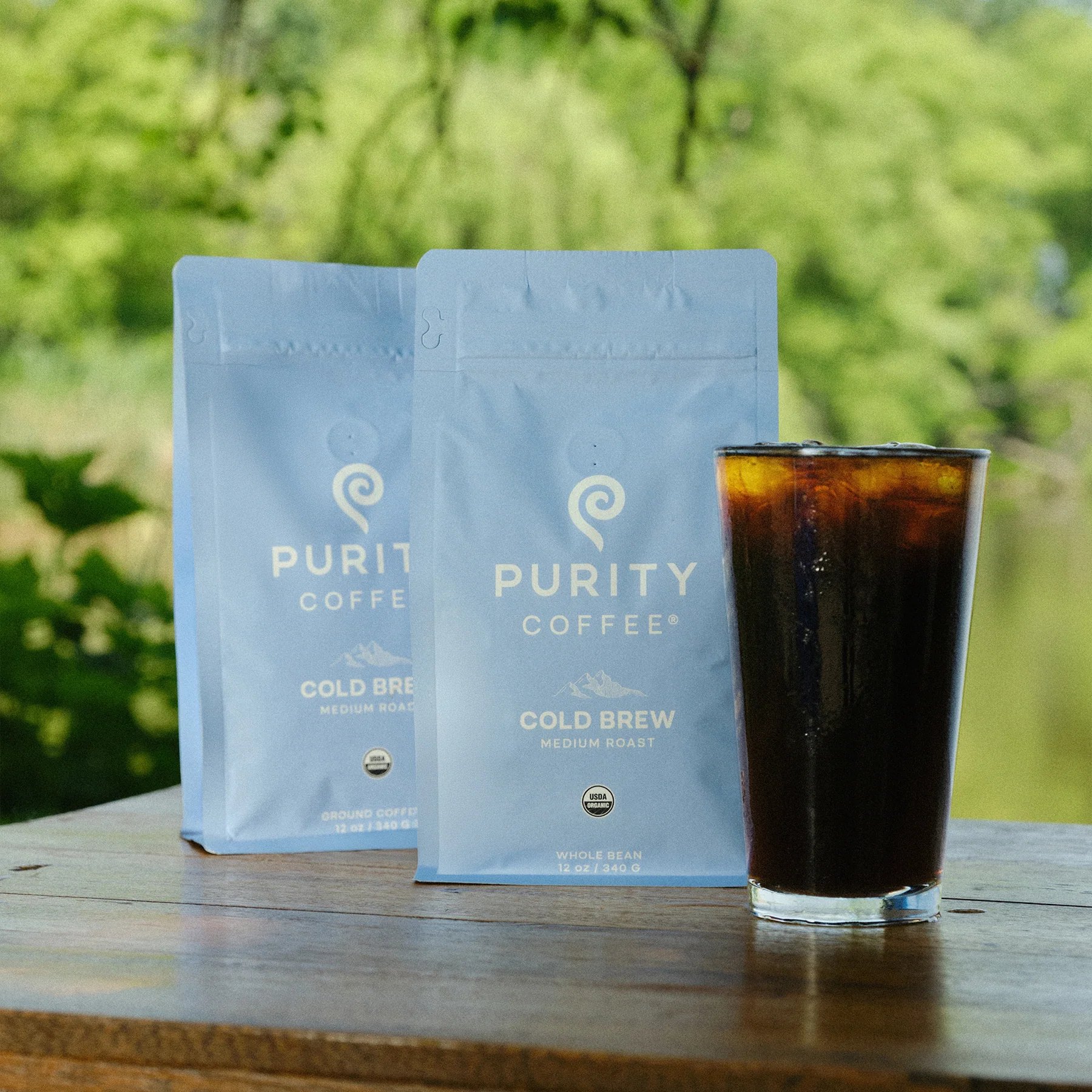 Purity Cold Brew pouches displayed with a tall iced coffee.