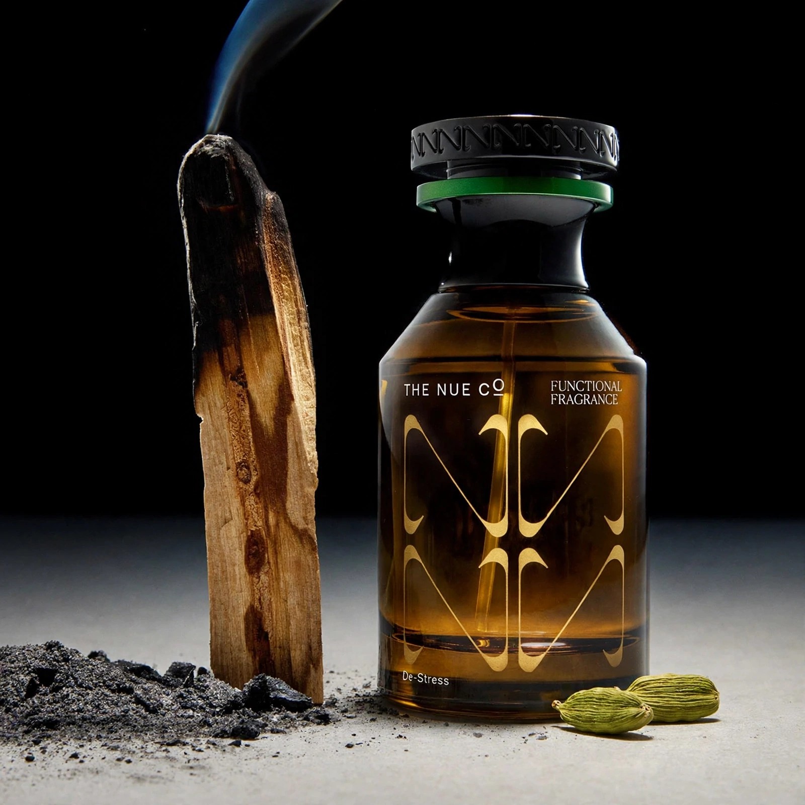 Styled image of scent bottle beside burnt wood.